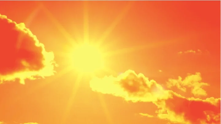 Bright sun in the sky with orange and yellow clouds during sunset or sunrise.