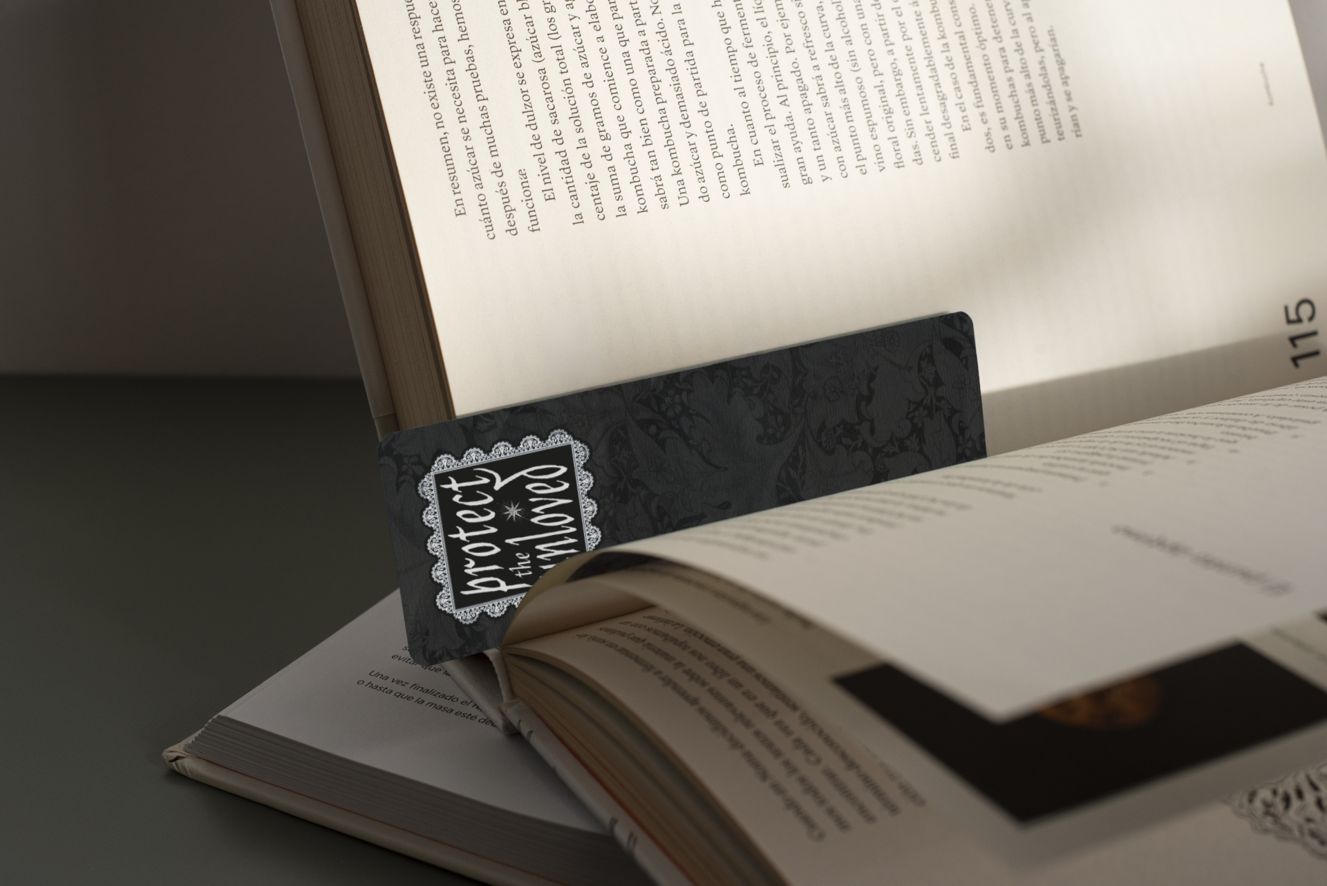 A black bookmark with white ornate decoration is displayed on an open book.