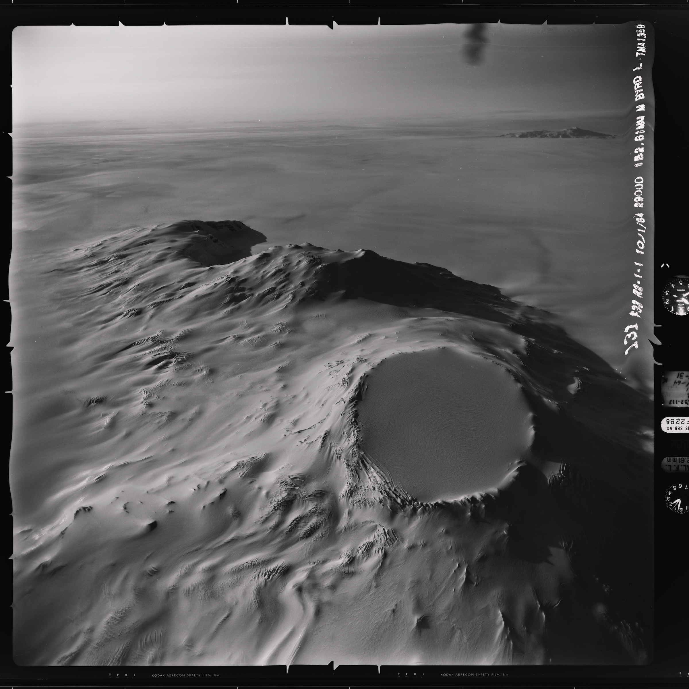 A black and white image of Mt. Takahe volcano on Thwaites Glacier in West Antarctica, with its round, snow-covered caldera visible and a black film frame around it