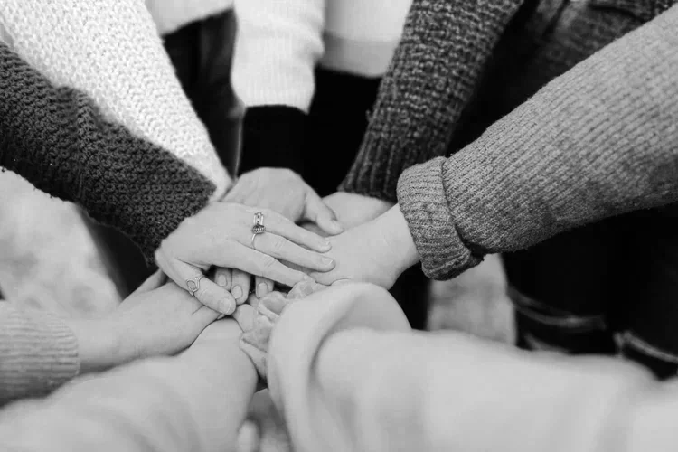 Multiple hands stacked one on top of another, demonstrating unity and teamwork.
