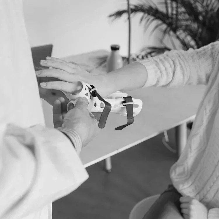 A person is receiving a medical device or orthopedic brace on their arm from a healthcare professional.