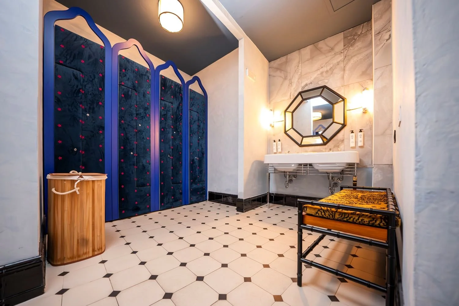 Spogliatoio con lavandino, specchio ottagonale, seduta a desco, cassapanca, cabine armadio con porte blu e rosa
