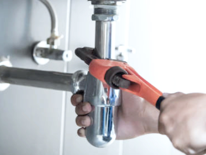 Person installing or repairing a plumbing pipe with a wrench.