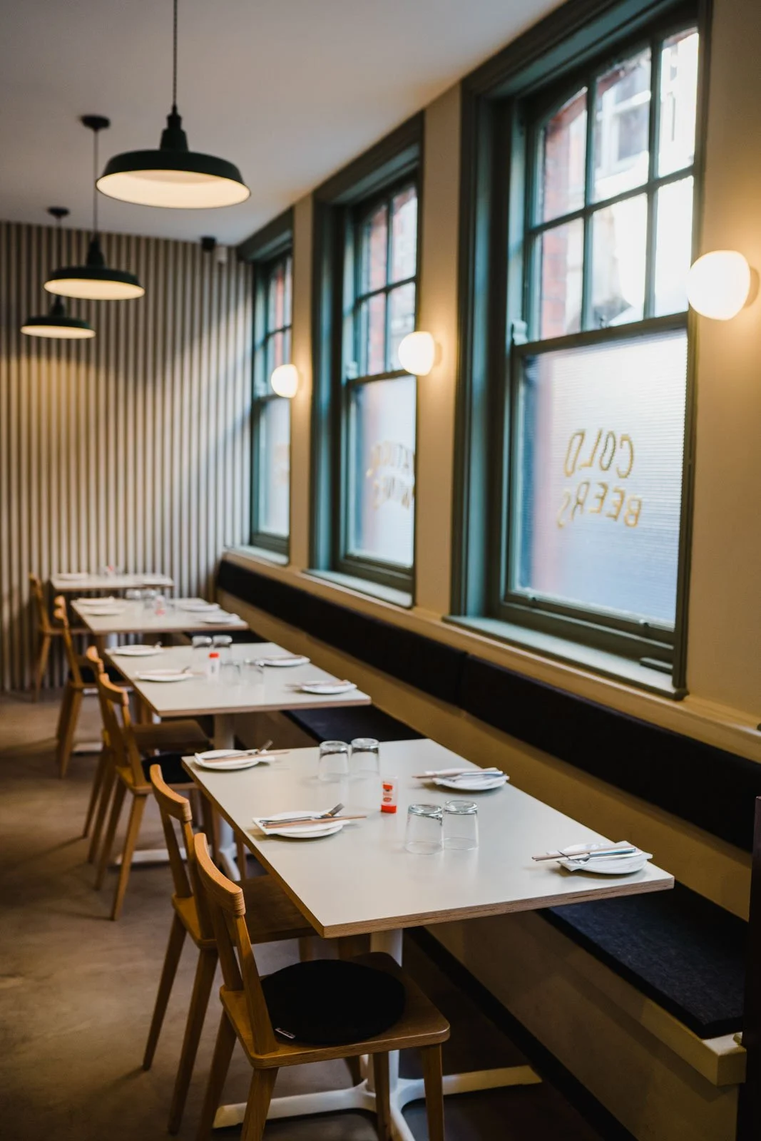 A row of 4 tables neatly aligned in a row, dressed with side plates and chopsticks ready for service