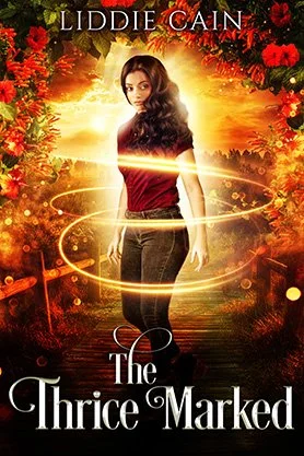 Paranormal fantasy book cover for “The Thrice Marked” by Liddie Cain, featuring a woman framed by fiery light and glowing golden rings in a warm autumn landscape.