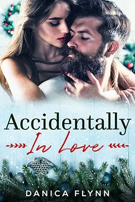 Romance book cover for “Accidentally In Love” by Danica Flynn, featuring a close-up of a couple embracing with winter greenery and festive details.