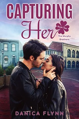 Contemporary romance book cover for “Capturing Her” by Danica Flynn, featuring a couple about to kiss in a romantic town street setting.