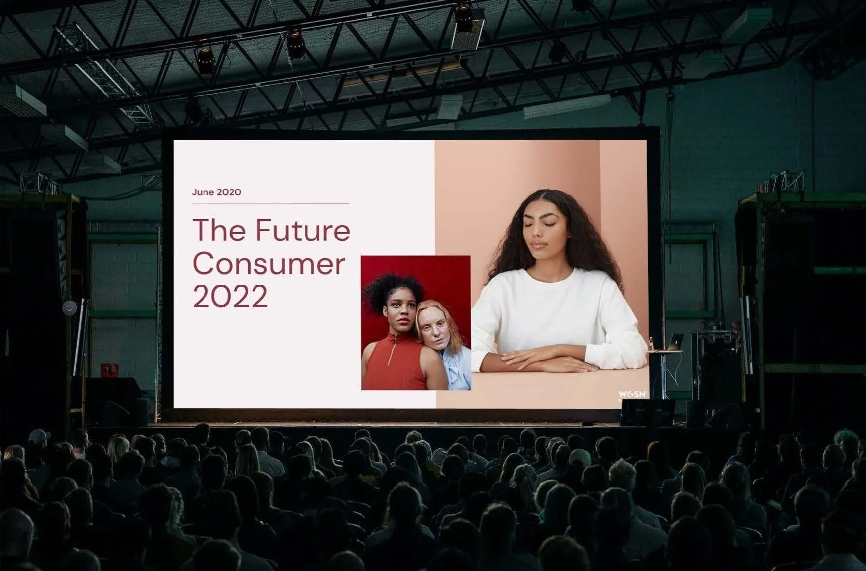 Large indoor presentation screen displaying a slide titled "The Future Consumer 2022" with images of diverse women and text indicating June 2020, in front of an audience.