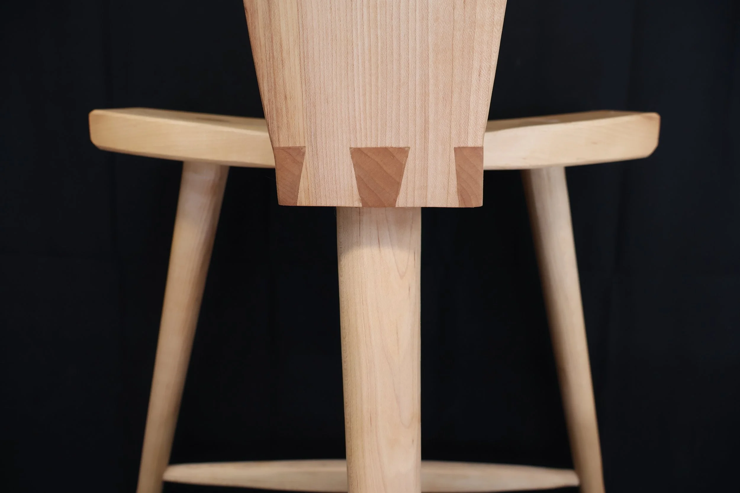 Close-up of a wooden chair with a black background.