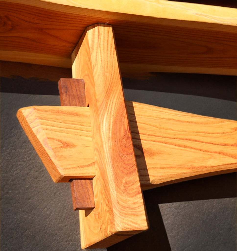Close-up of intersecting wooden beams with a natural finish, showing the grain and texture of the wood, set against a dark background.