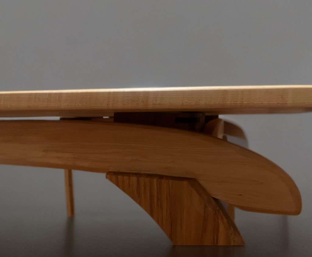 Close-up side view of a wooden table leg and support structure, showing craftsmanship in the woodwork.