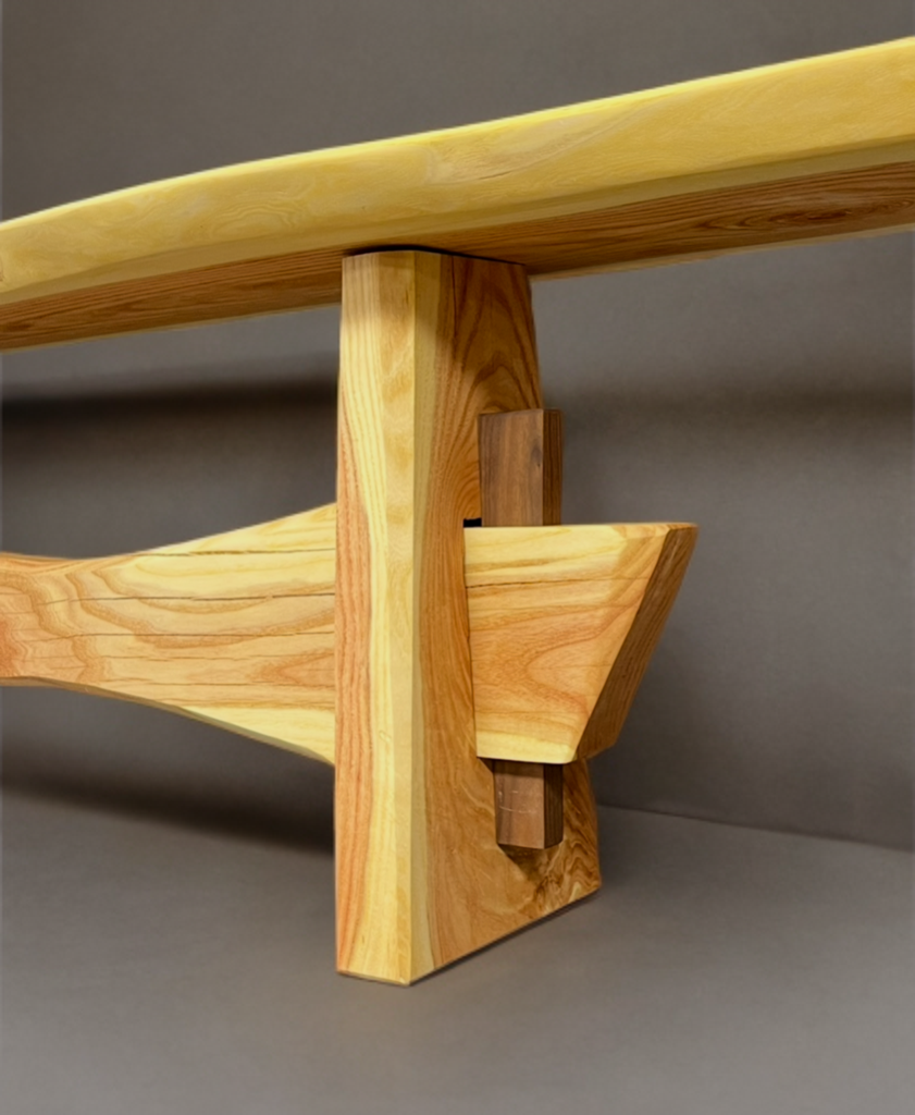 Close-up view of a wooden piece of furniture or structure, showing detailed joinery in light-colored and darker wood with a smooth finish.