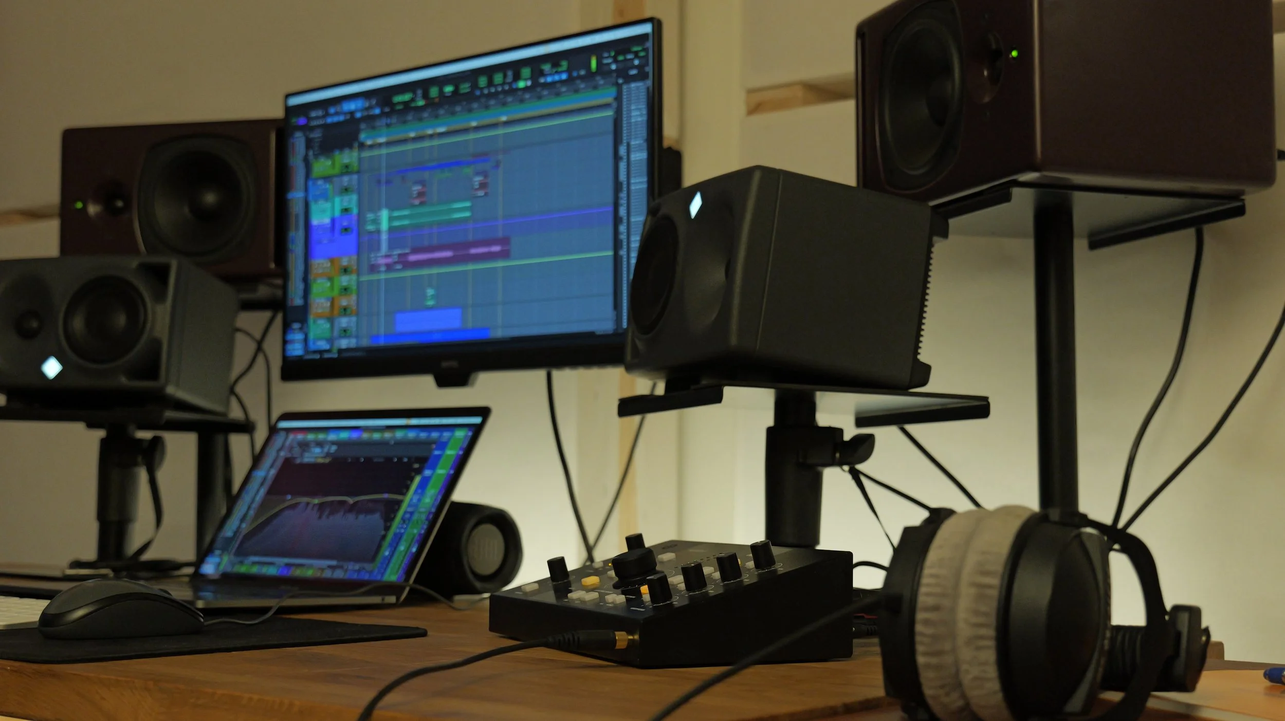 Configuration d'un studio d'enregistrement avec ordinateur, haut-parleurs, casque audio, contrôleur de musique et logiciel de production musicale.