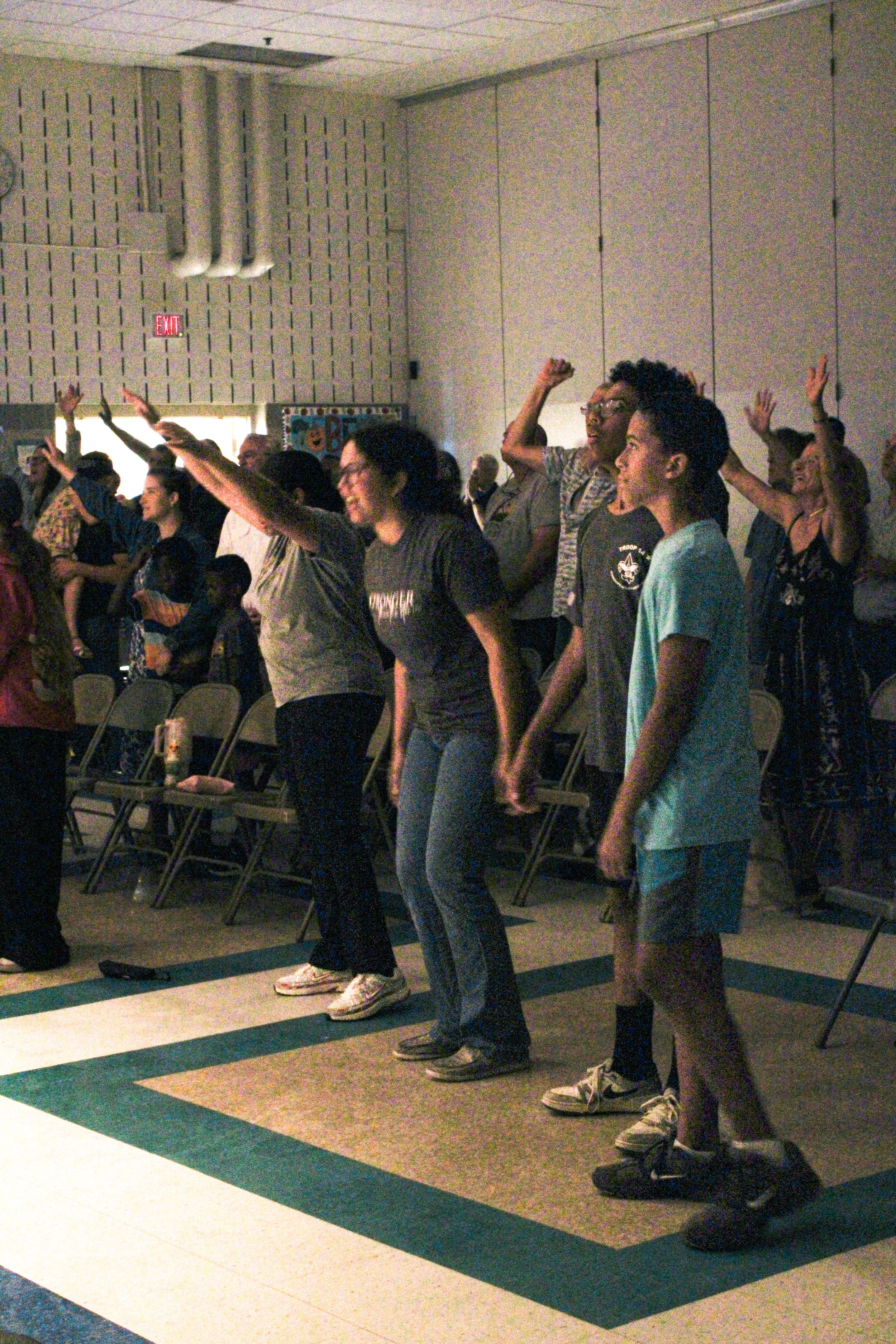 A group of people worshiping God in a dimly lit room.
