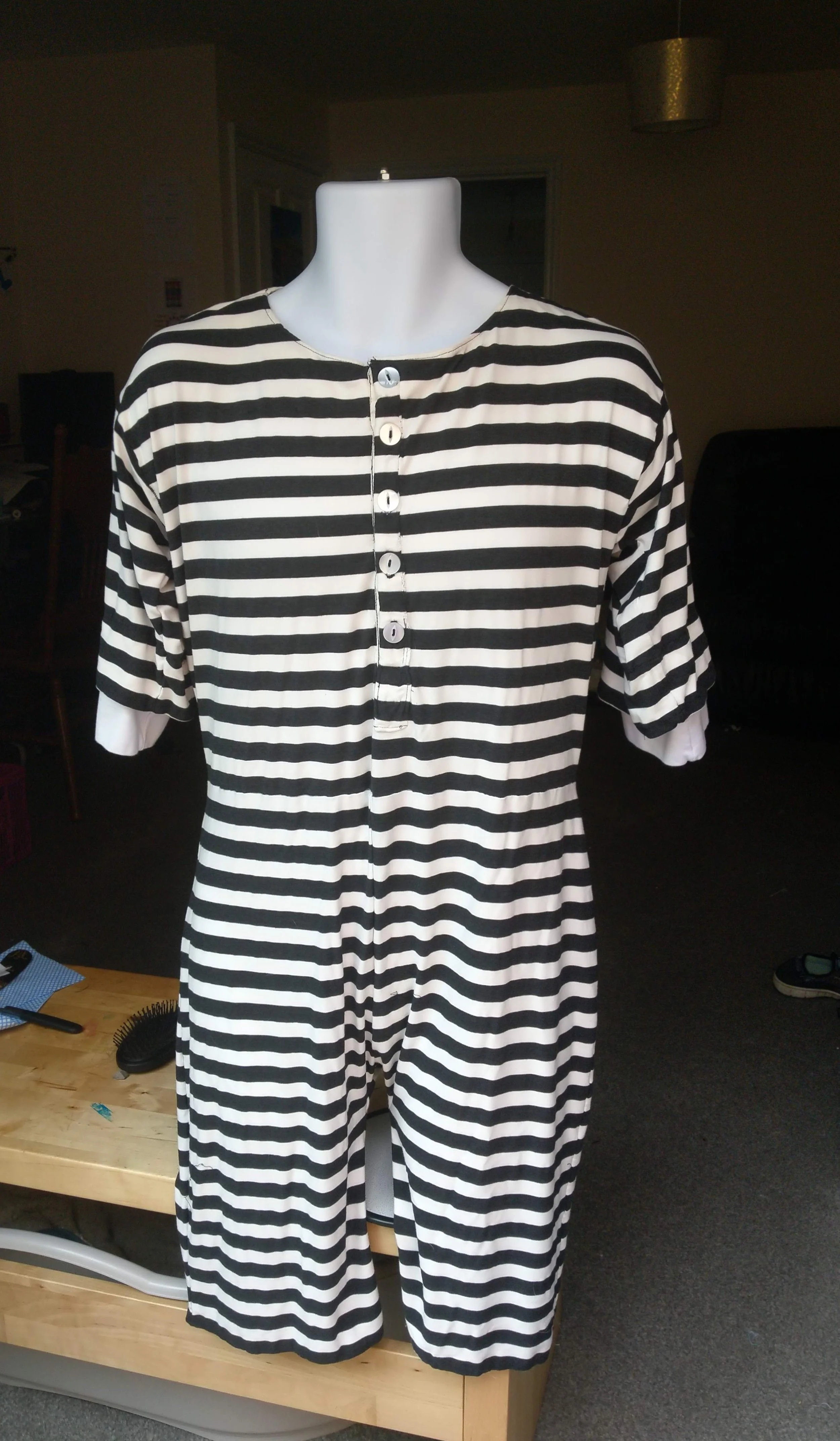 Striped black and white dress on a mannequin, with buttons down the front, in a room with furniture and a light fixture.