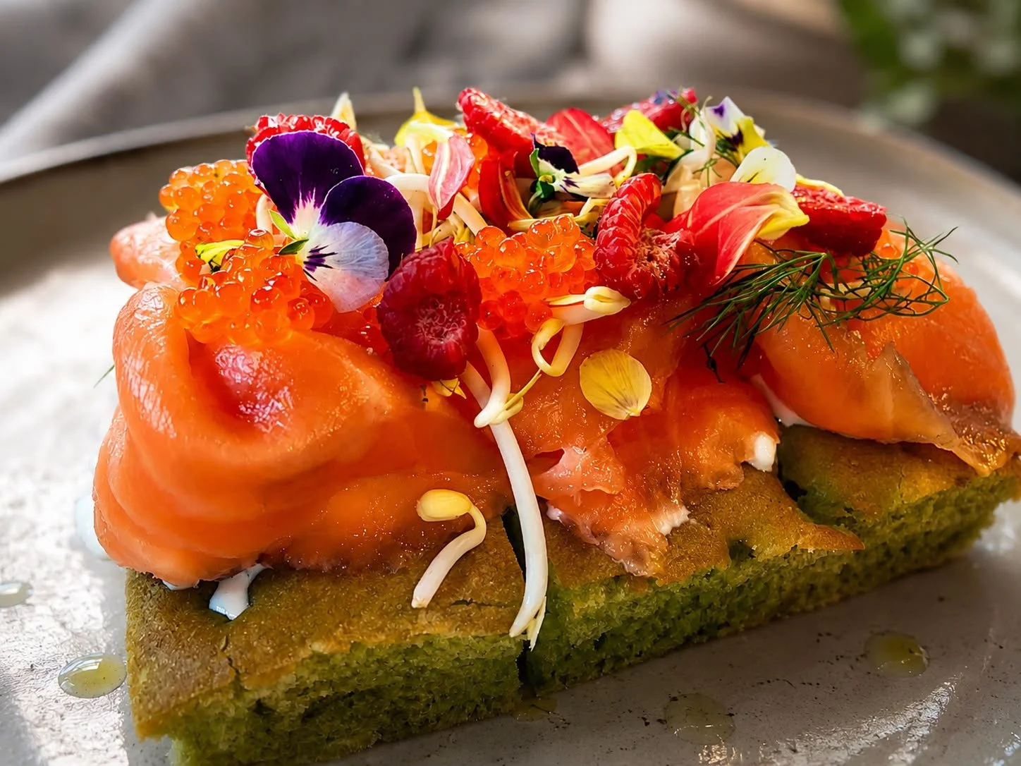 Focaccina con salmone, fiori eduli, frazioni di frutta e erbe aromatiche