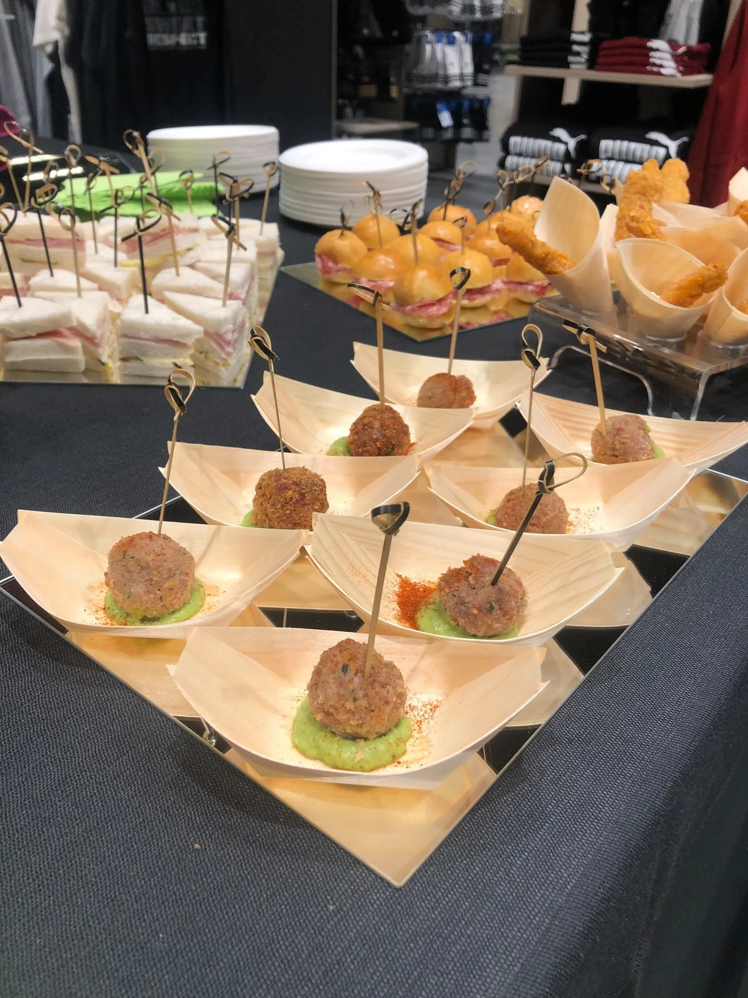 Assorted finger foods and snacks, including mini sandwiches, croquettes, and canapés, arranged on a table for a catering event.