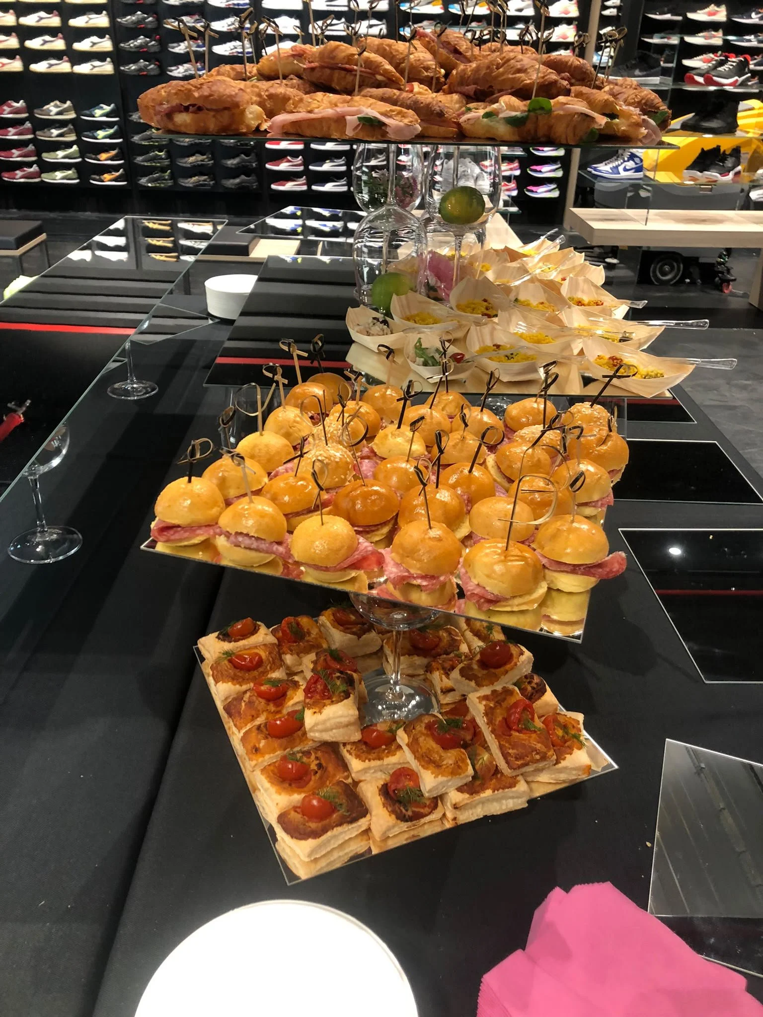 Un buffet con vari canapè, mini burger e pizzette in un negozio di scarpe.
