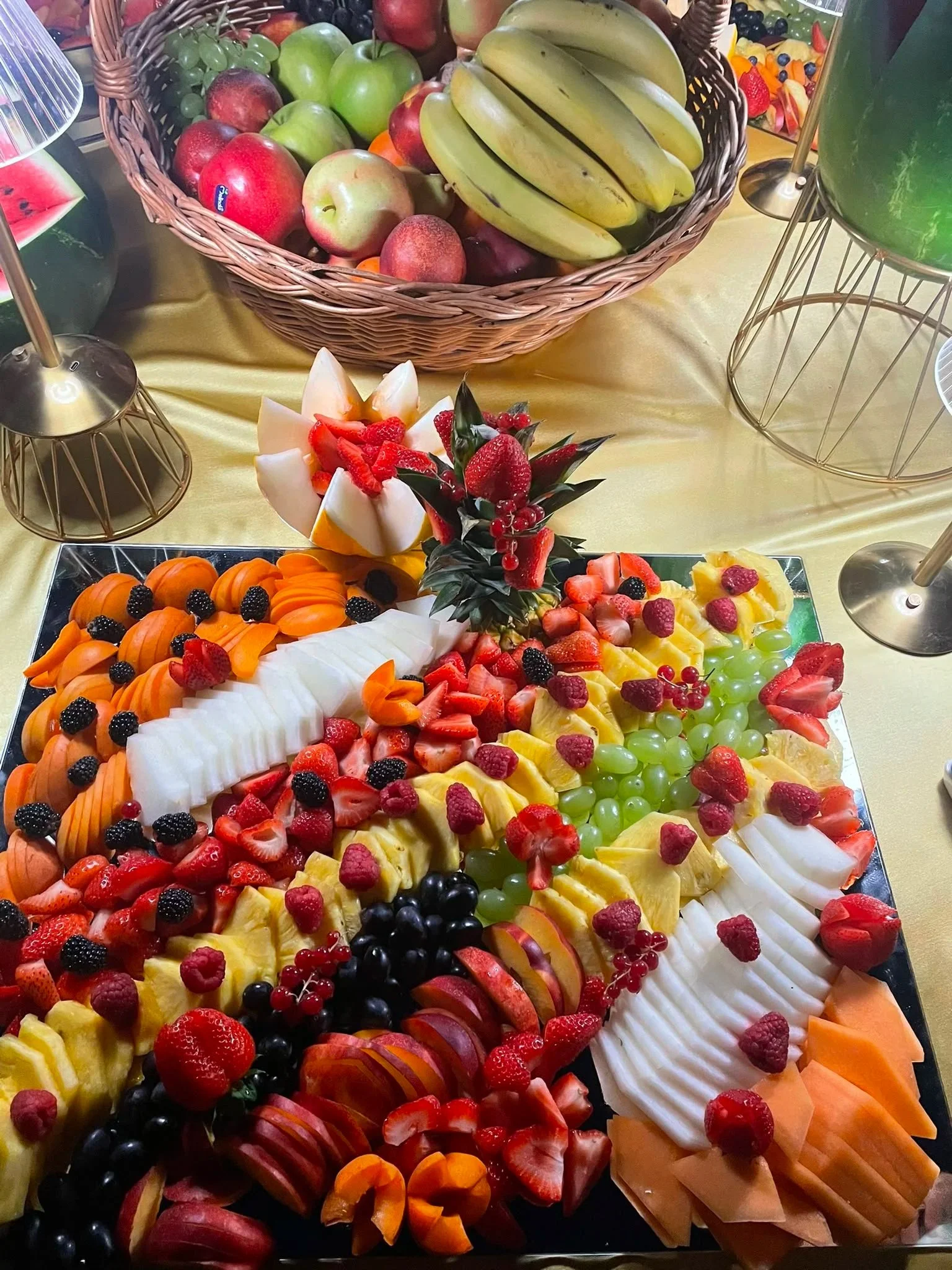 Vassoio con fettine di melone, fragole, lamponi, mirtilli, ananas, uva verde e nera, albicocche, decorato con cuori di frutta fresca su specchio.