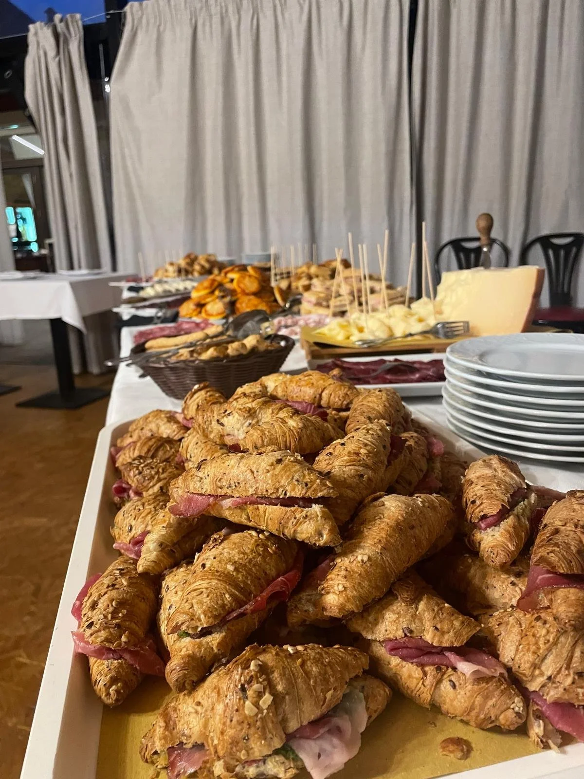 Croissant salate gourmet, Focaccine e altri antipasti affettati e formaggi su un tavolo buffet.