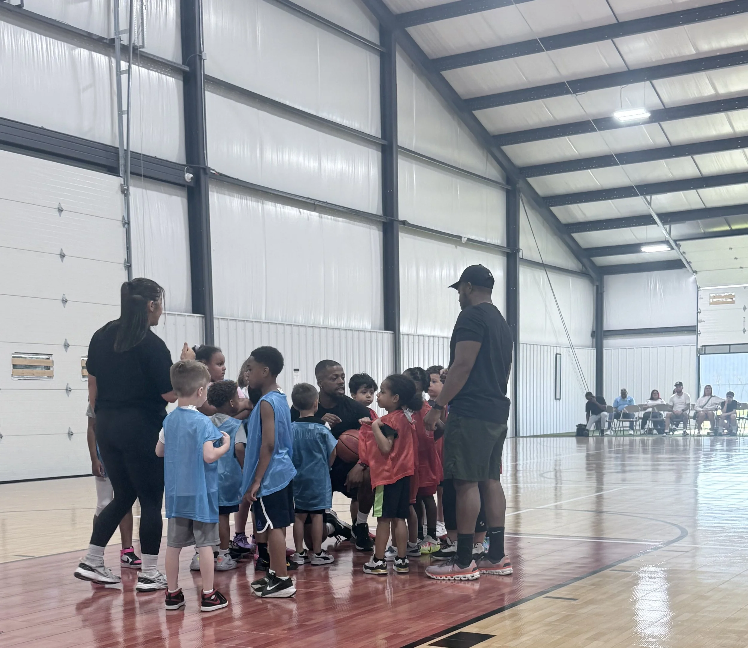 Children gathered with coaches on an indoor basketball court during a Gary Family Foundation youth program.