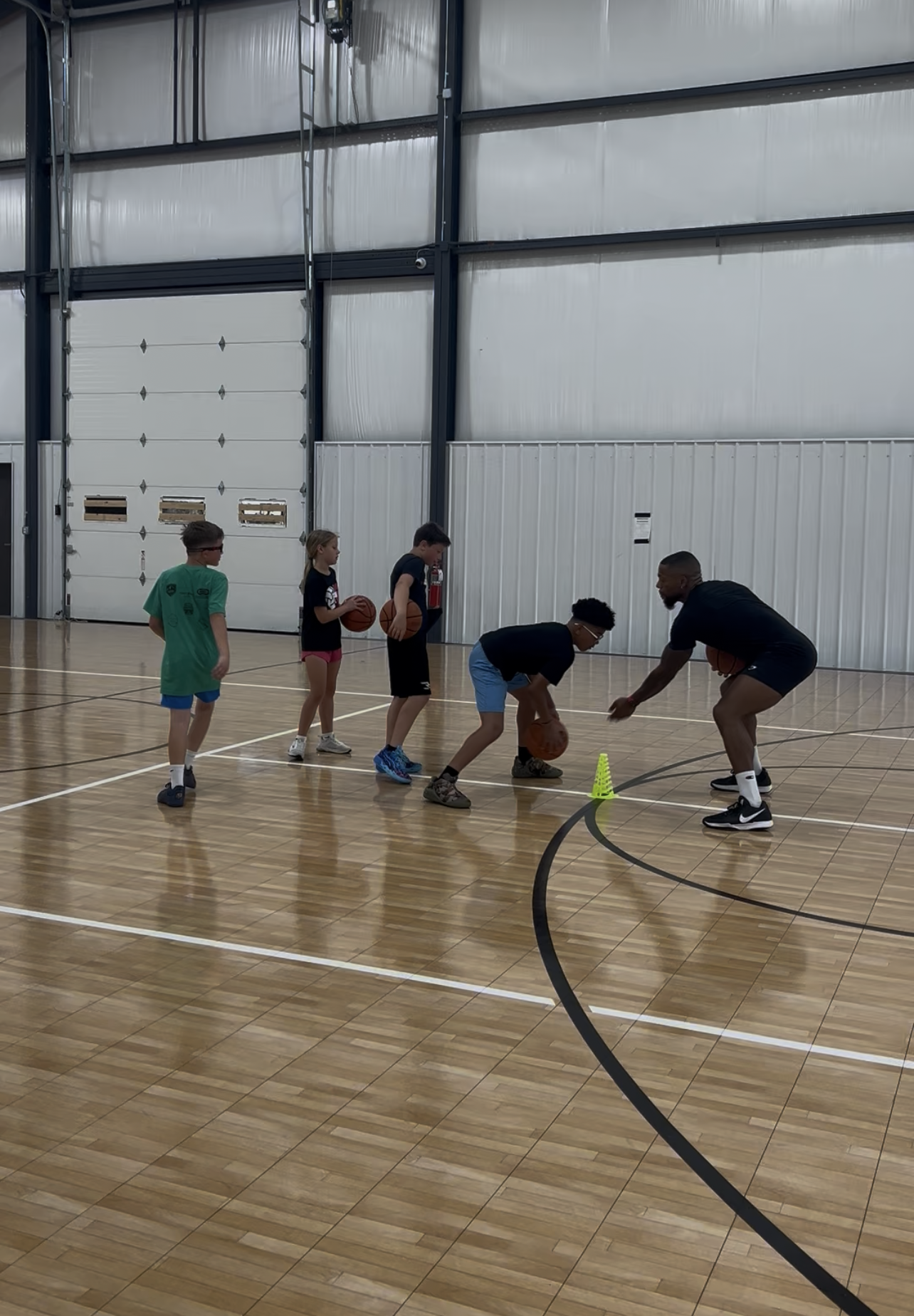 Coach leading children through a basketball drill during a Gary Family Foundation youth sports program.