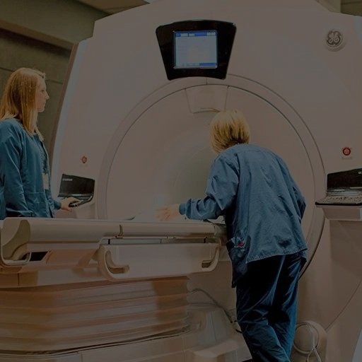 A medical technician assists a patient in an MRI machine.