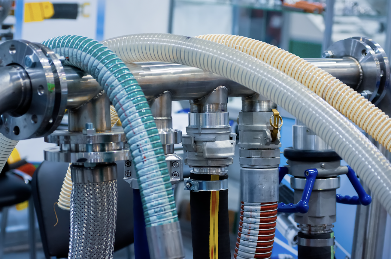 Industrial hoses and pipes connected to metal fittings in a mechanical setup.