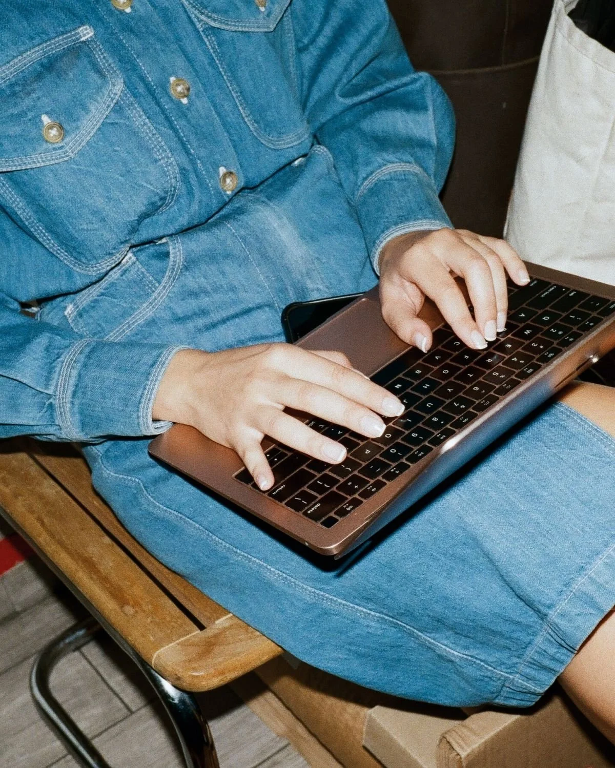 Persona che utilizza un computer portatile mentre è seduta su una sedia di legno.