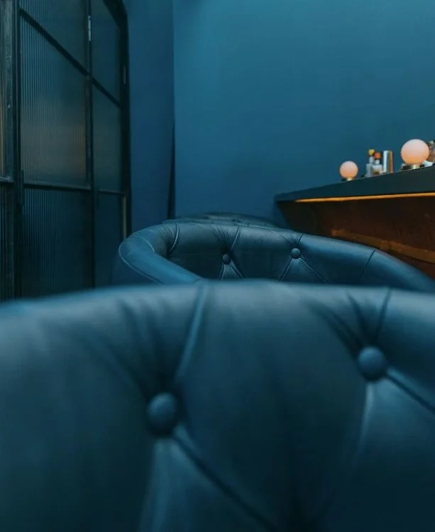 Hospitality interior with deep blue leather seating and warm decorative lighting.