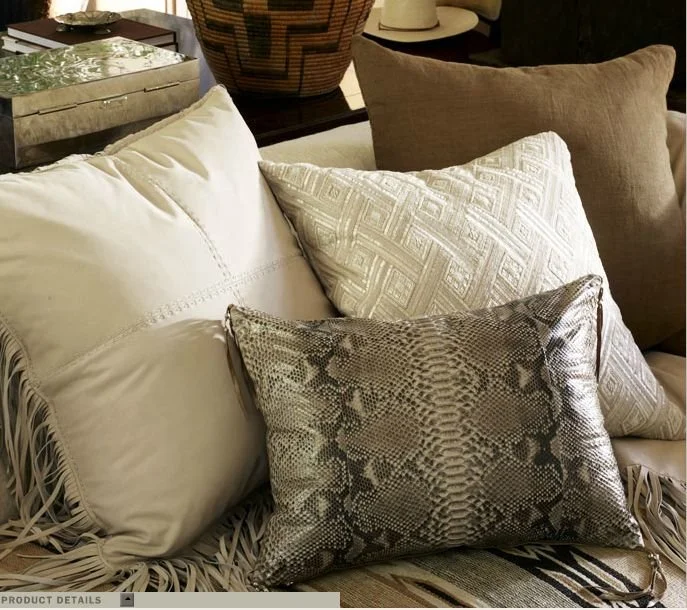 Decorative sofa pillows featuring a python-pattern leather pillow with deerskin fringe.