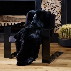 Black shearling draped over a chair in a contemporary interior.