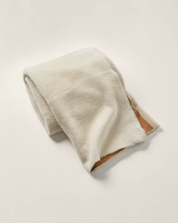 Folded cream Spanish Merino shearling throw on a light background.
