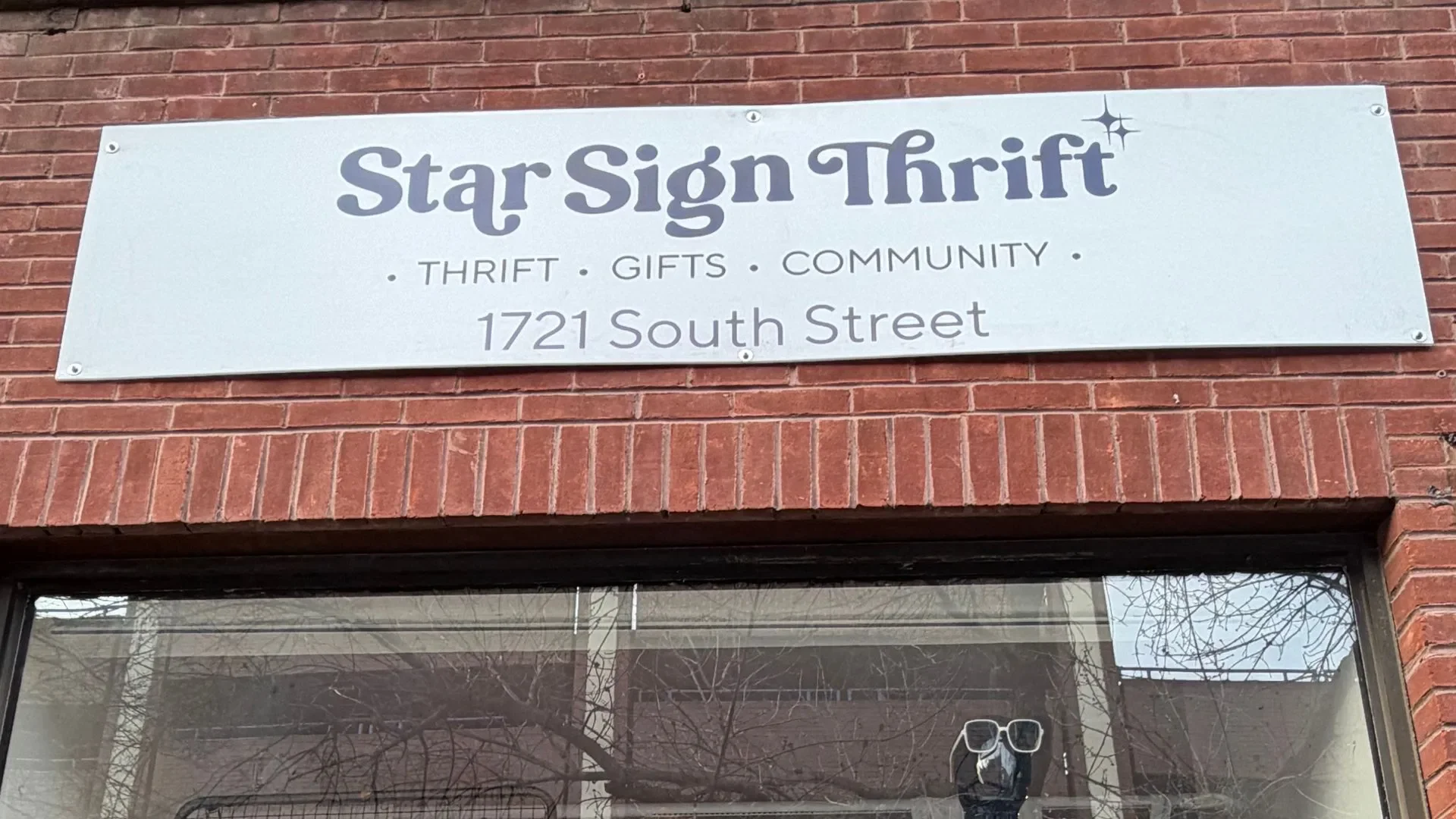A white sign on a brick wall reads 'Star Sign Thrift, Thrift Gifts Community, 1721 South Street'.