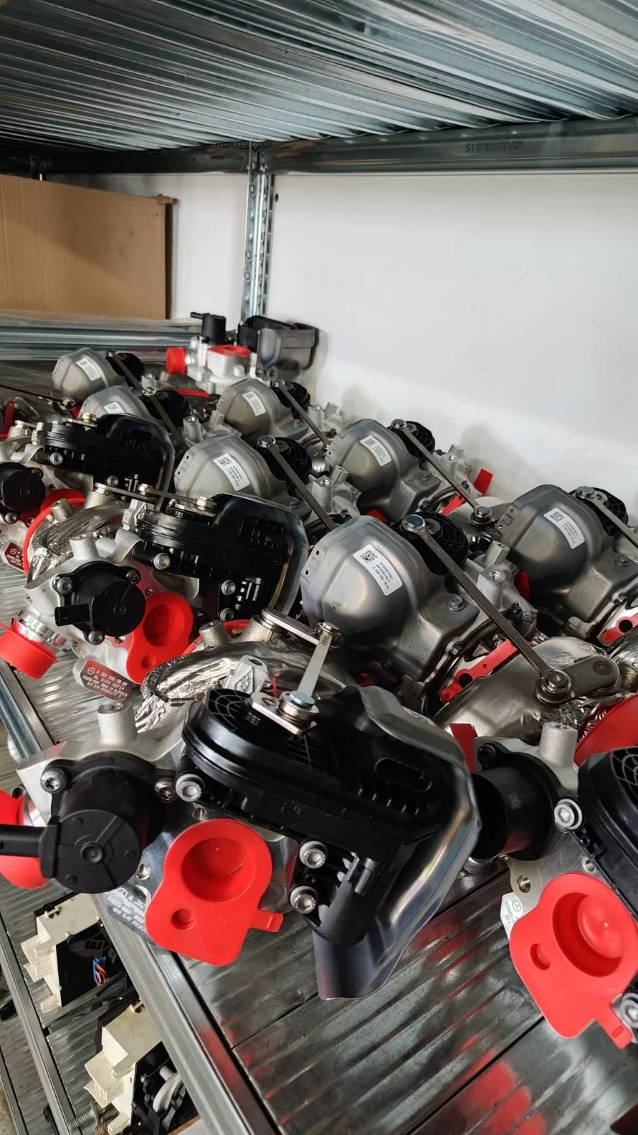 Multiple automotive engines or motor units placed on a metal workbench in a workshop or industrial setting.