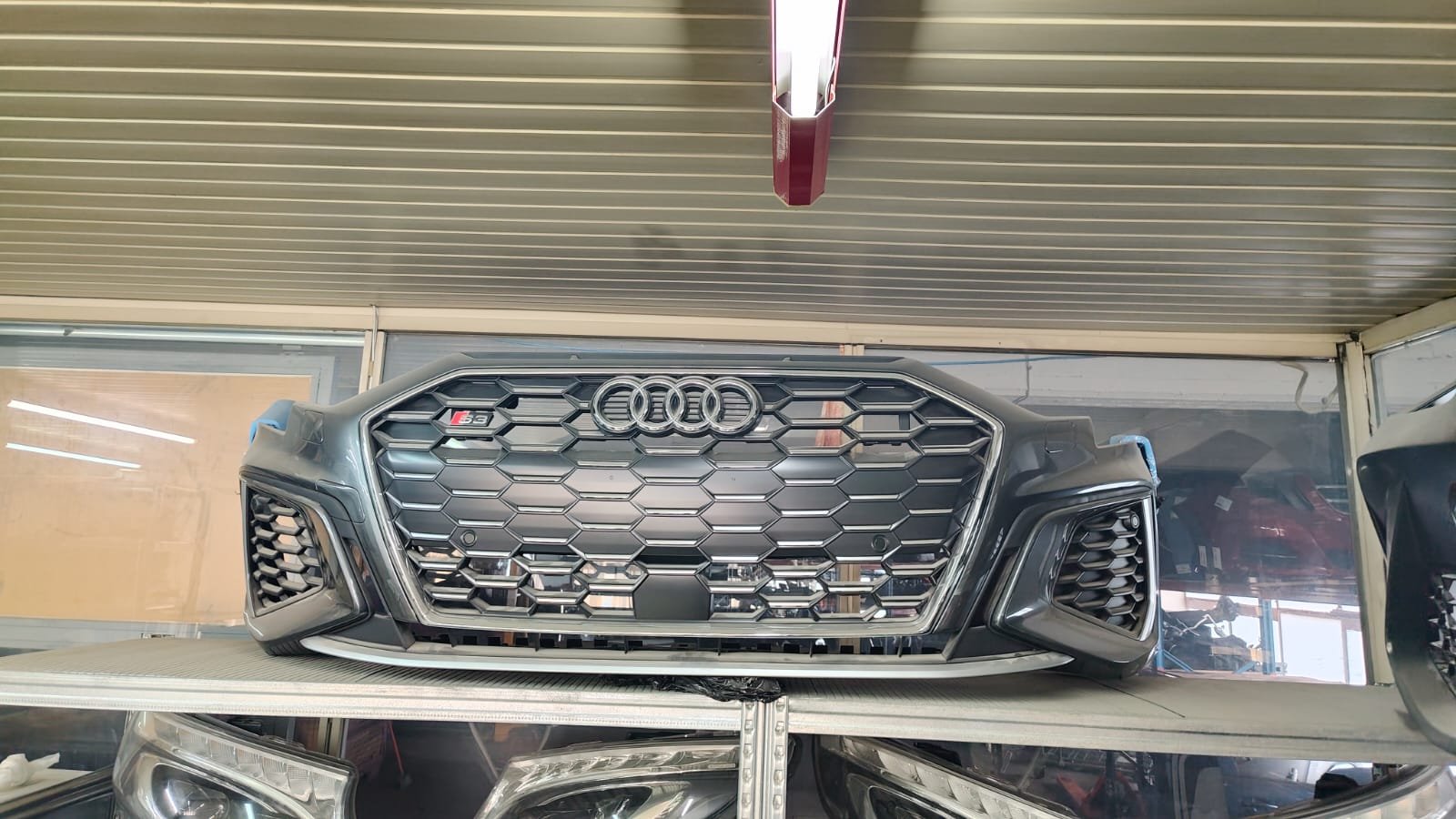 Front grille of a black Audi S3 car on display in a showroom.