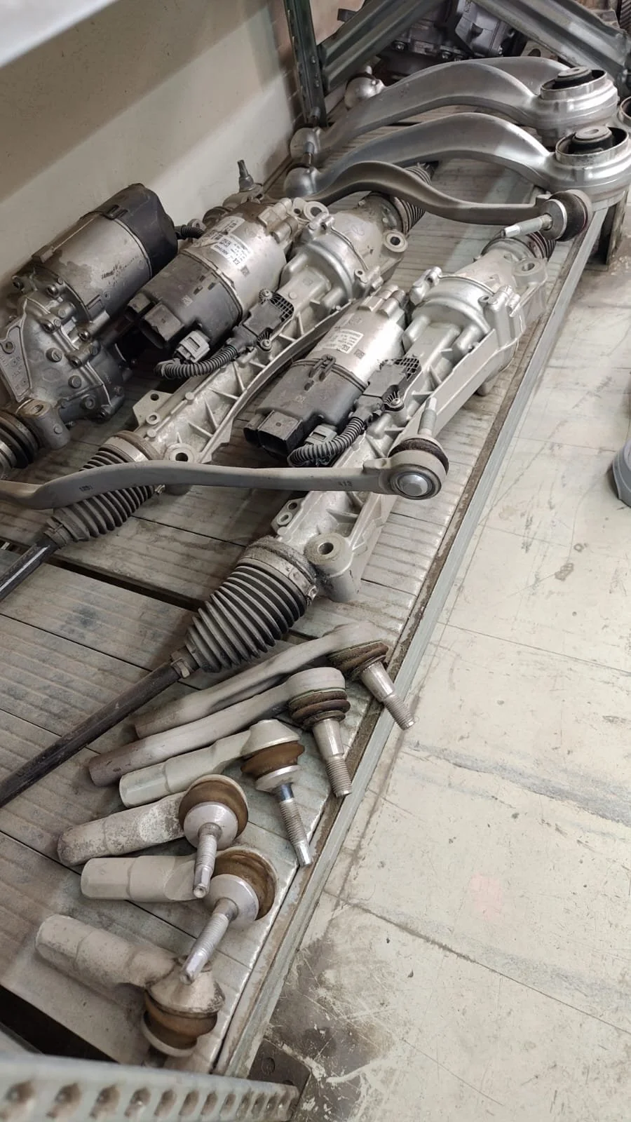 Collection of automotive parts, including multiple motor assemblies and various suspension components, laid out on a workbench.