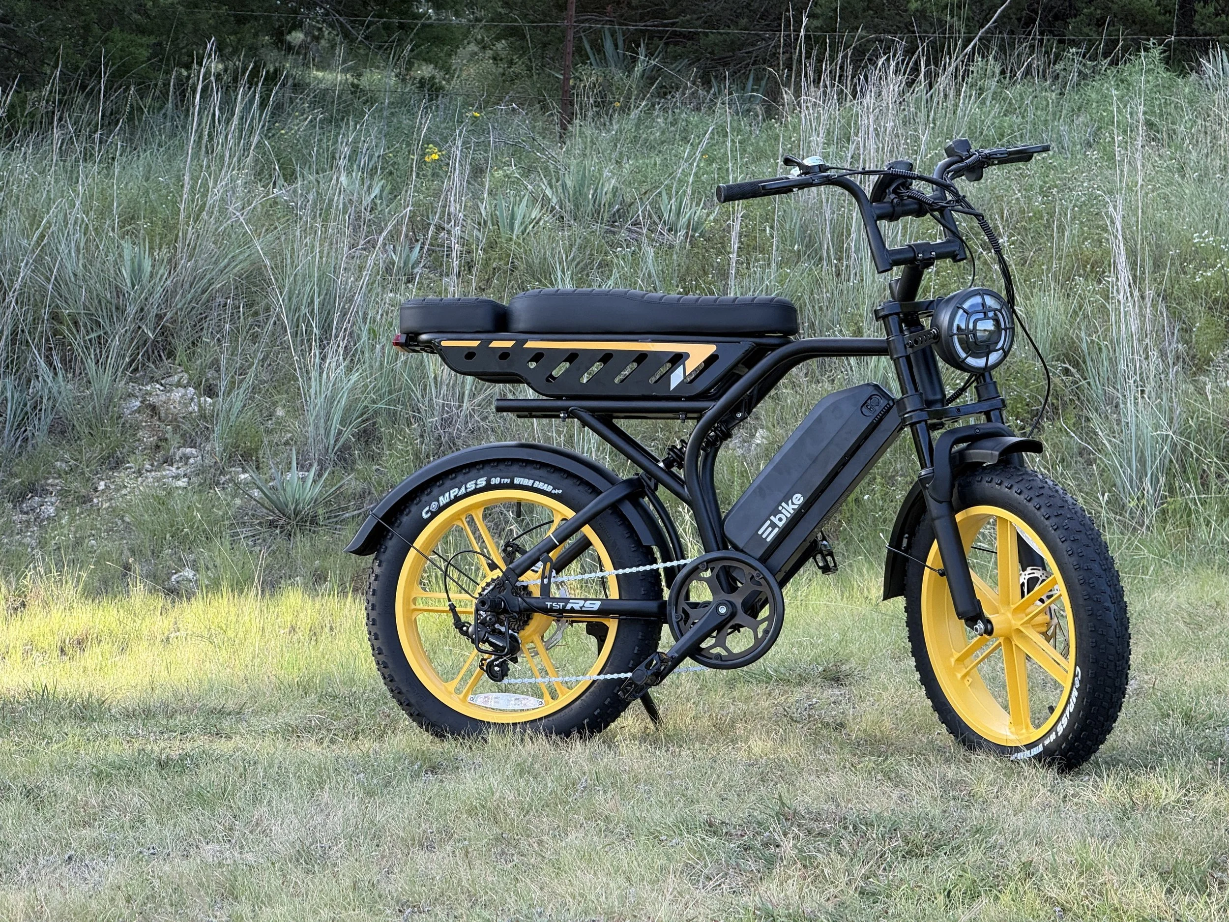 Black-and-yellow electric bike parked on grass outdoors.