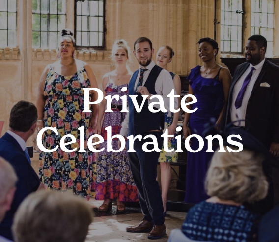 A group of well-dressed people standing in a room with large windows, during a private celebration or event.