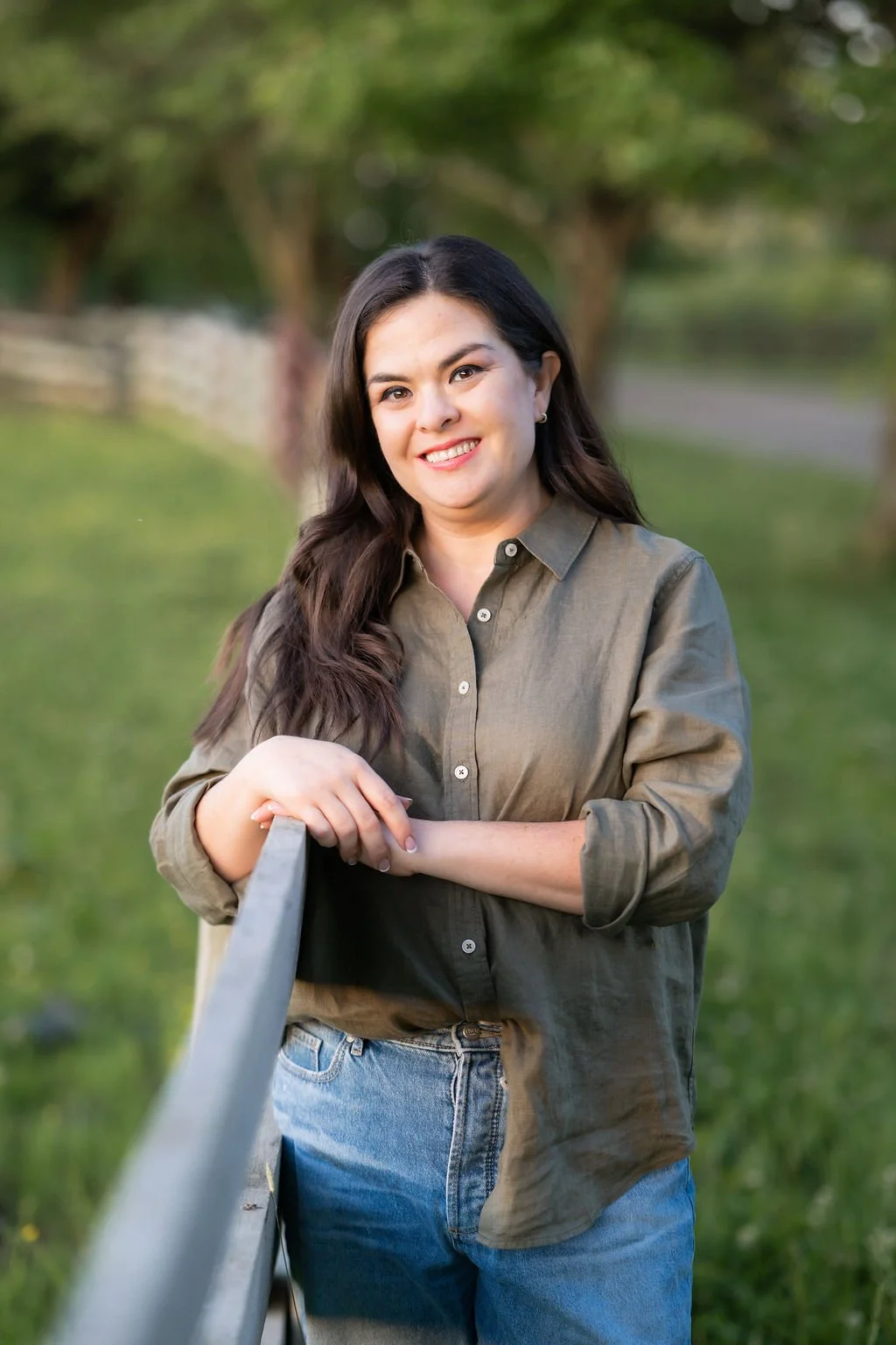 Image of Brittany Vera, LCSW, trauma specialist, a woman with long dark hair in an olive green button down shirt leaning against a fence