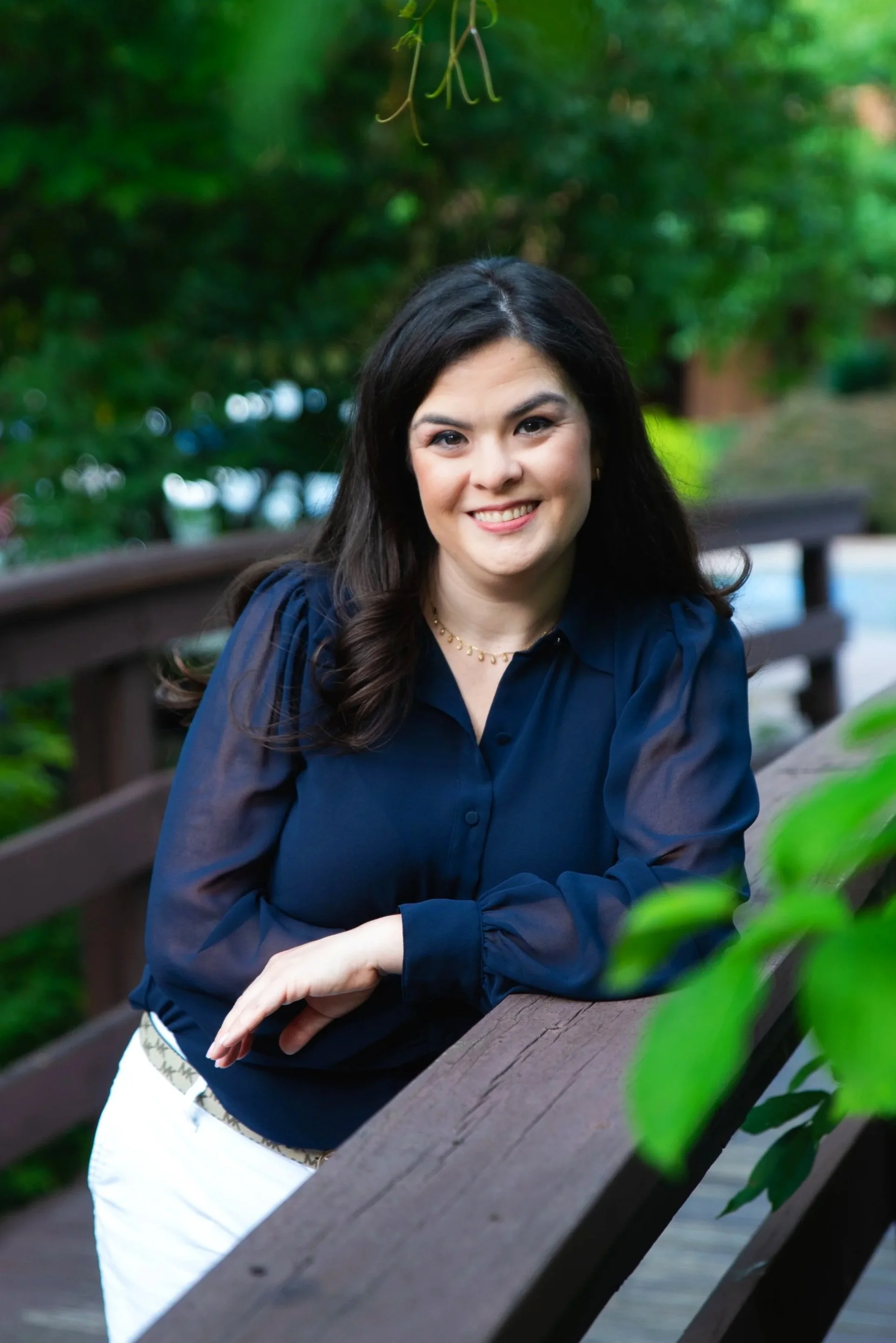 Image of Brittany Vera, LCSW, trauma specialist, a woman with long dark hair in a navy blue blouse leaning on the railing of a bridge.