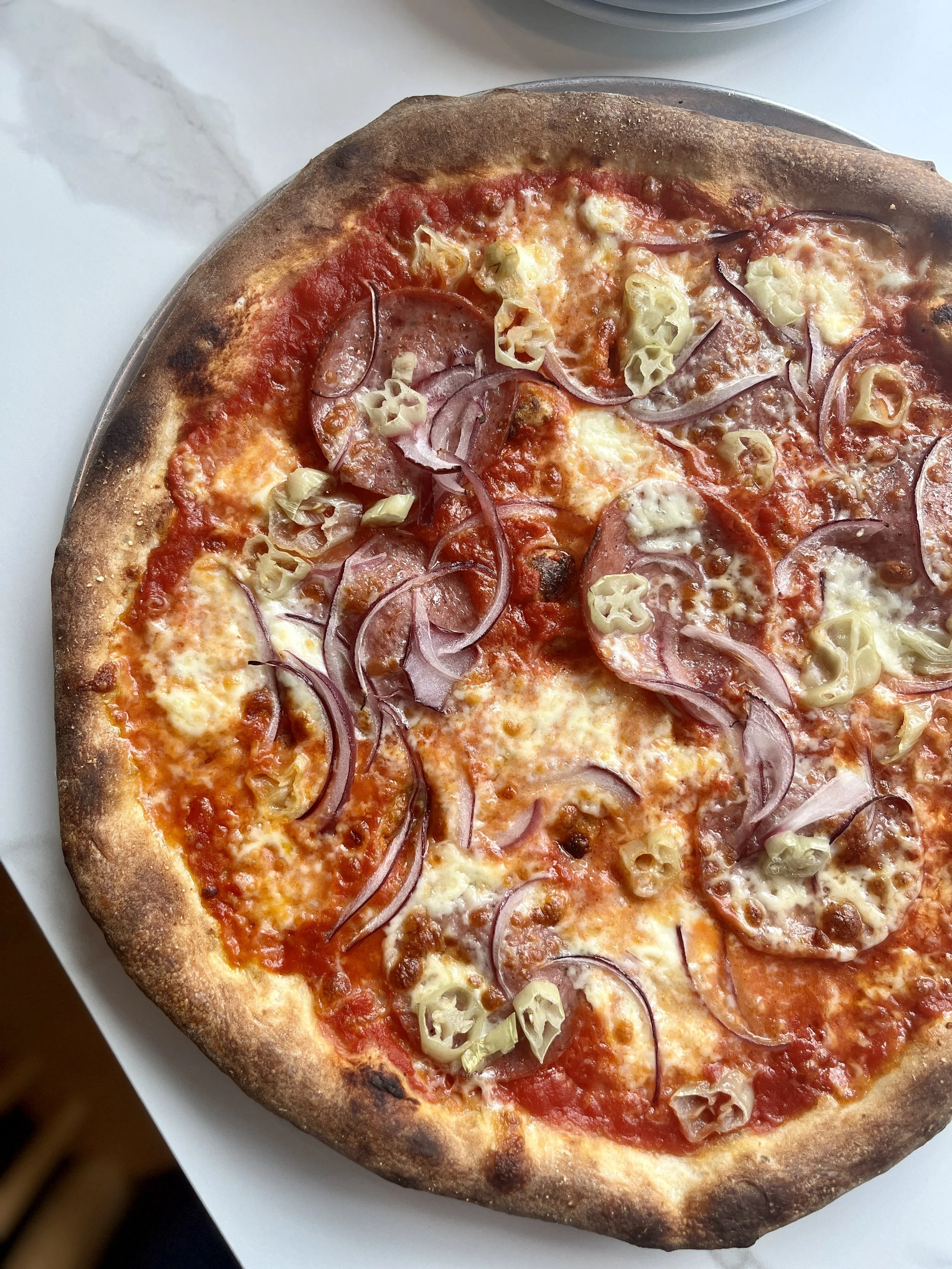 Close-up of a pepperoni and onion pizza on a white plate.