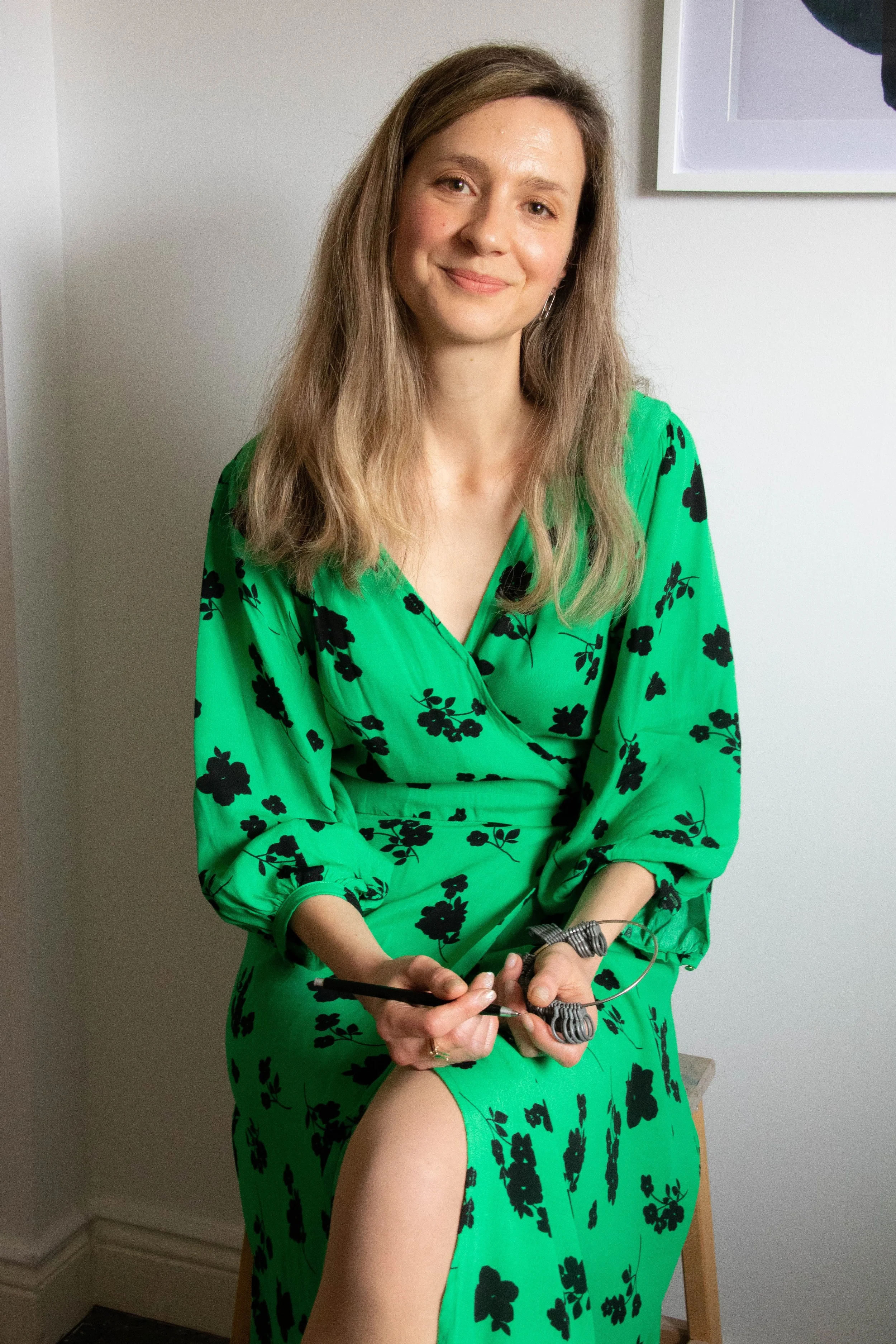 Designer Julie Lawlor wearing a green dress and holding ring sizer.