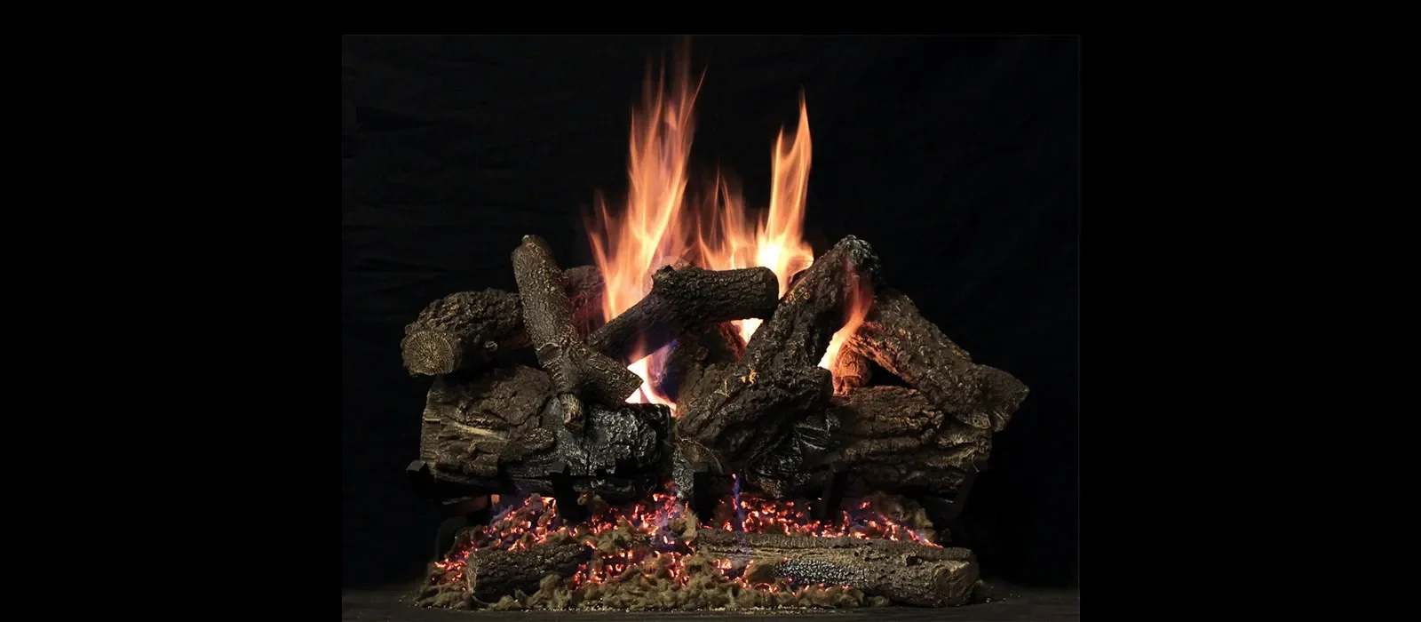 Wood logs stacked on a fire with bright flames and embers against a dark background. Gas logset. Gas fireplace. Gas Insert.
