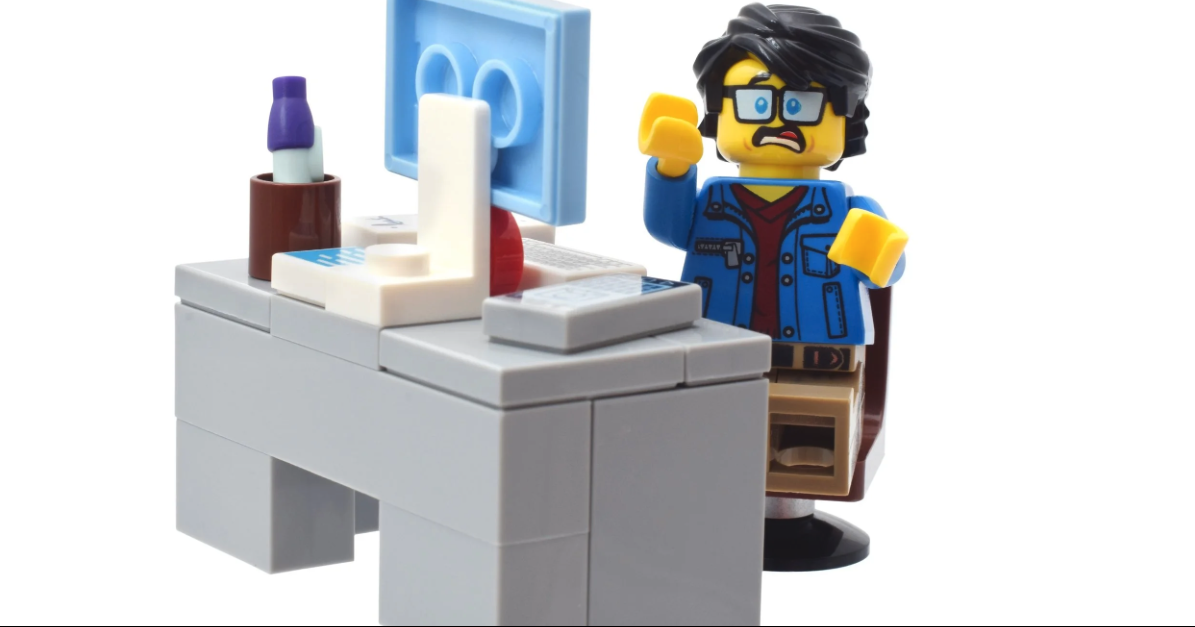 Frantic male lego worker sitting at a work desk