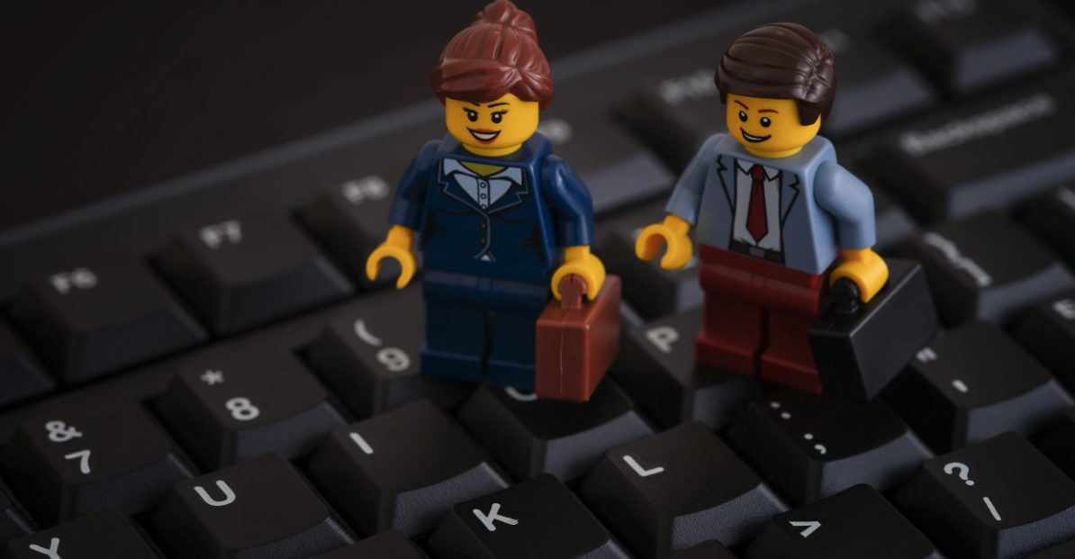 Two lego businesspeople walking across a computer keyboard