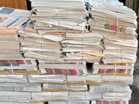 Stacks of bundled newspapers stacked outdoors.