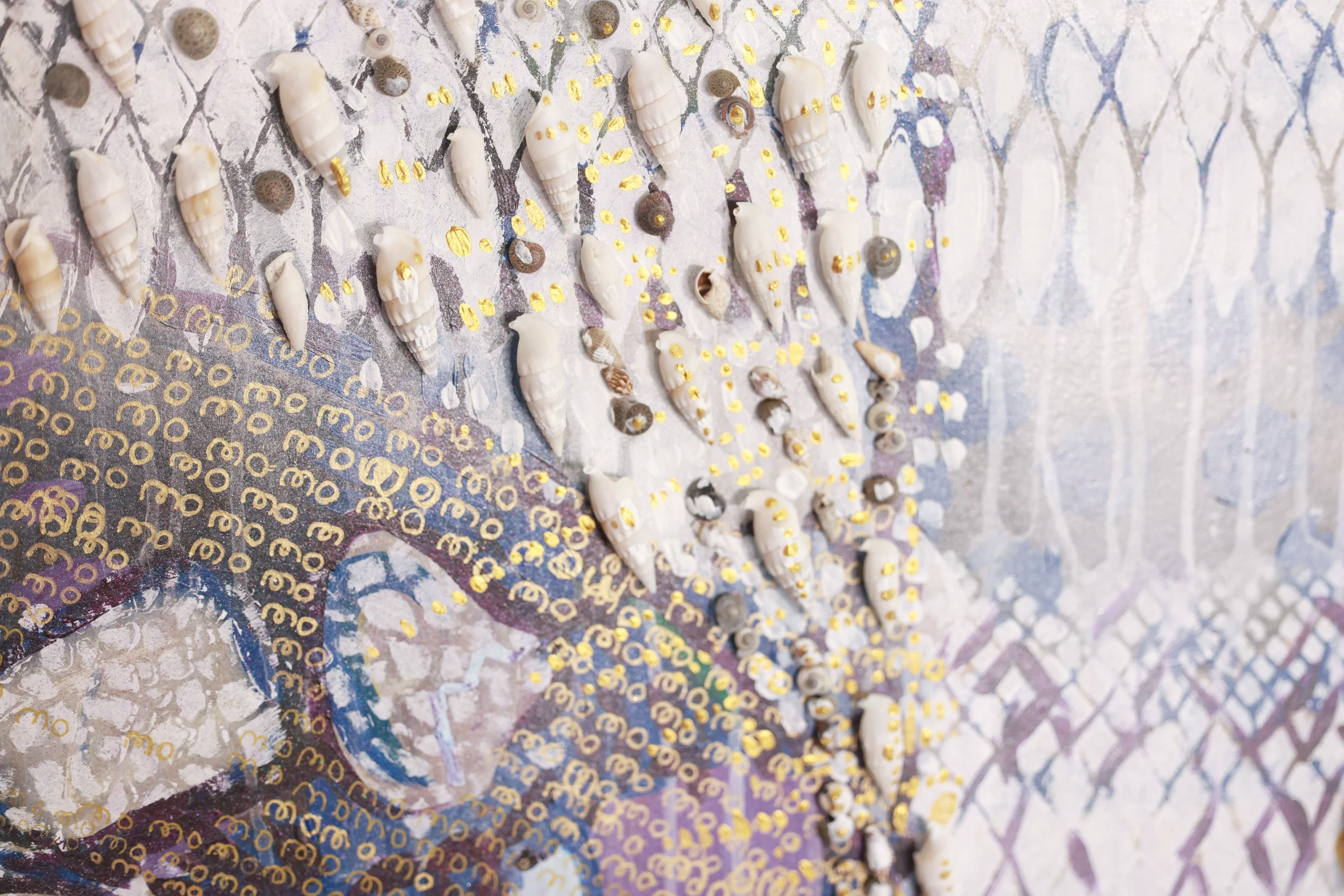 Close-up of a mosaic featuring small seashells and gold paint accents on a colorful, patterned background.