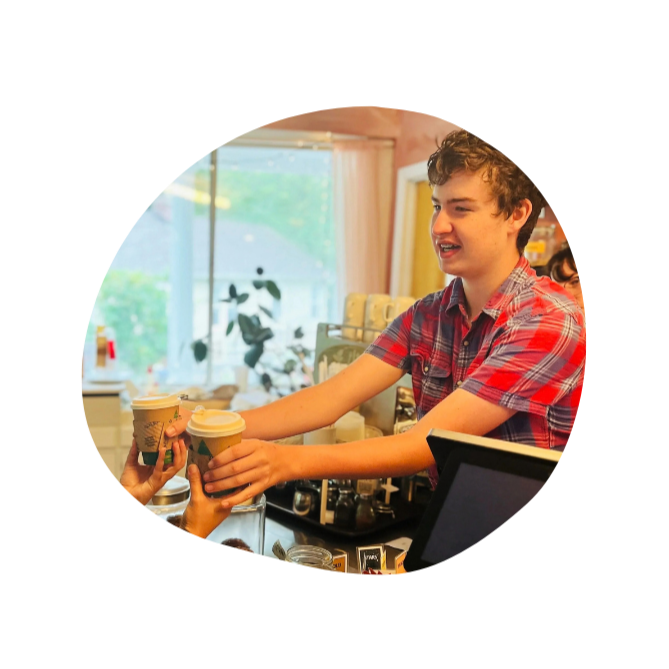 A high school boy at Otto Specht School serving a coffee to someone with a smile on his face.
