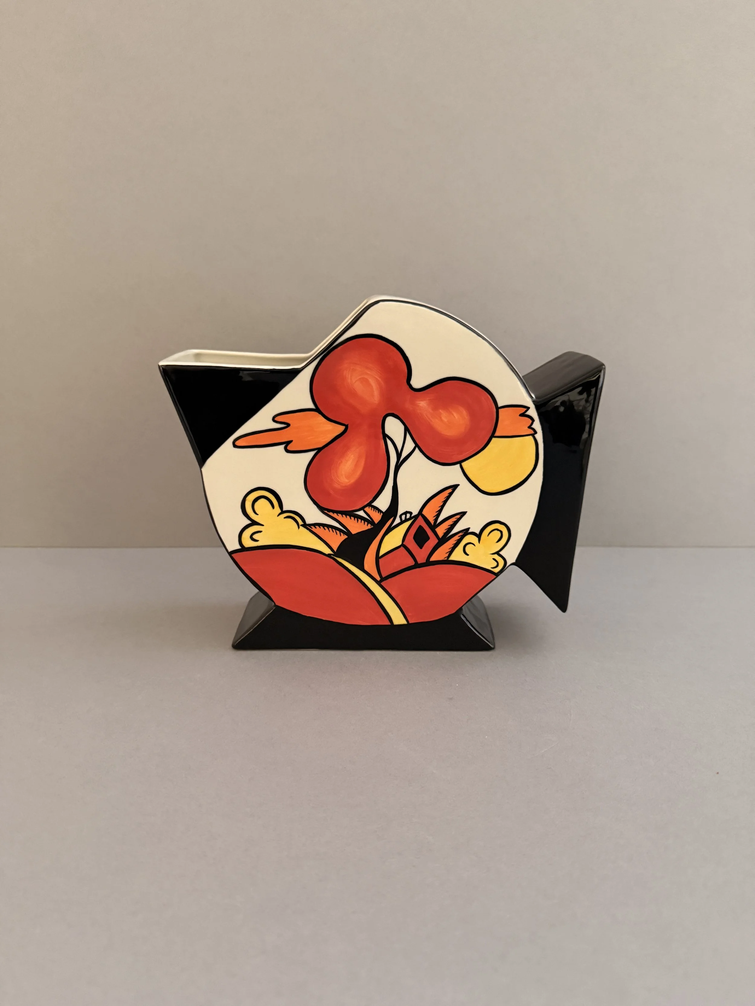 Decorative object with a colorful abstract design, featuring red, orange, yellow, and black elements, on a neutral gray background.